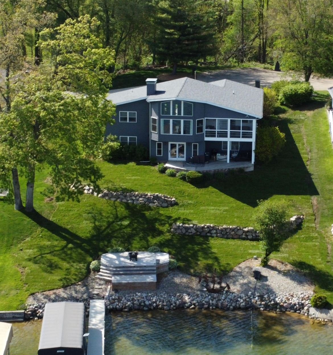 Aerial drone view of a finished lakefront yard with boulder wall and fire pit area