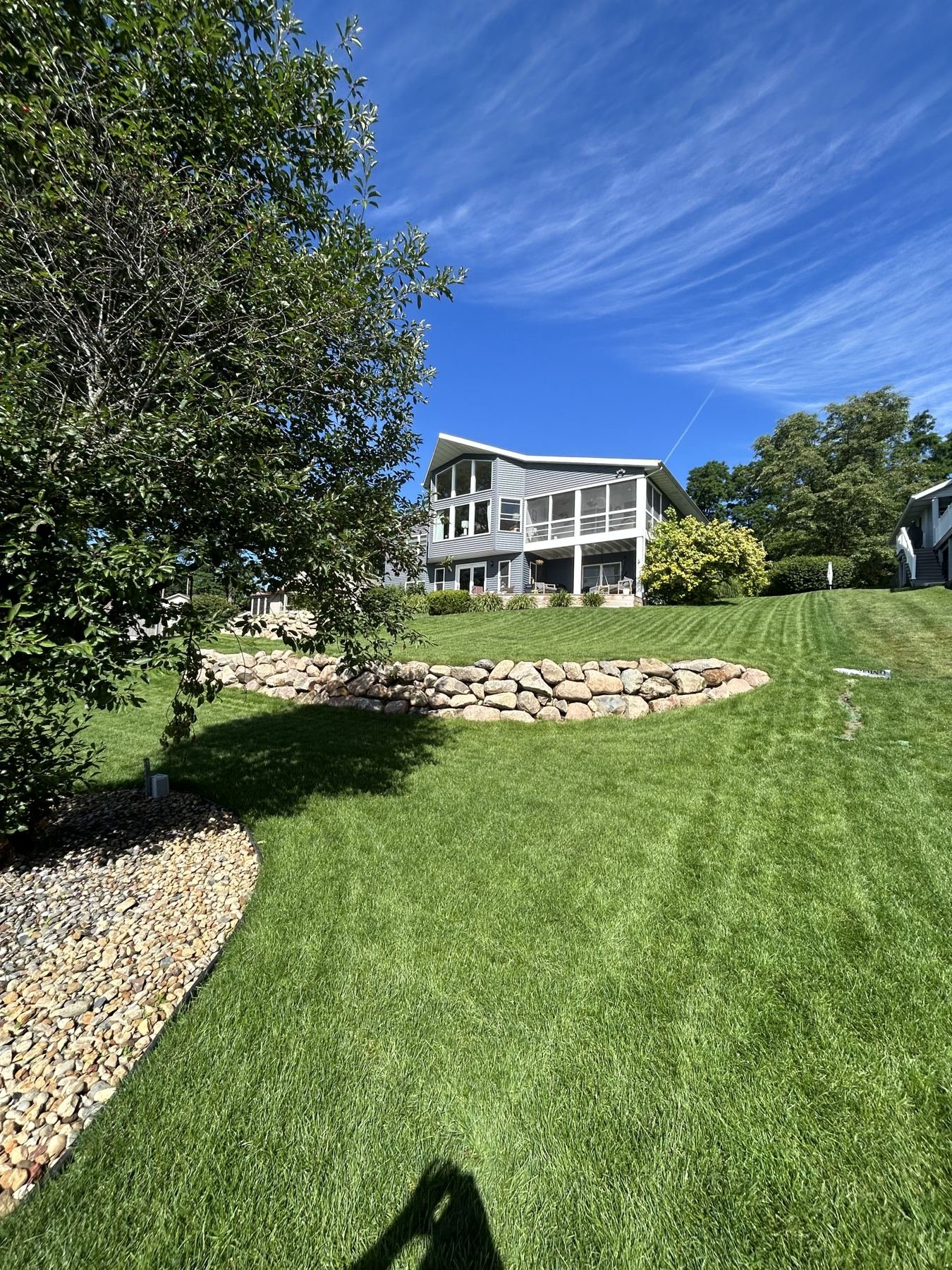 After: curved boulder wall, river rock beds and striped lawn